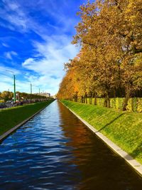 Trees by river against sky during autumn