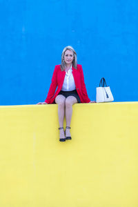 Portrait of mature woman with purse sitting on retaining wall