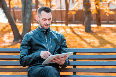 Young man looking away while sitting on bench