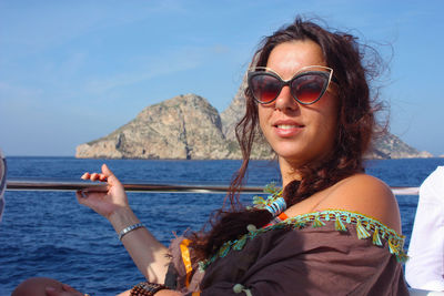 Caucasian girl traveling by boat on the ibizan sea and a rocky cliff behind in balearic island