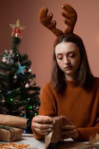 Portrait of young woman sitting on christmas tree at home