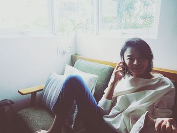 Young woman sitting on sofa at home