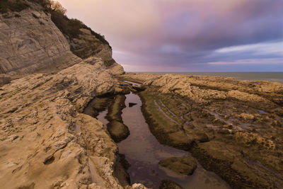 Rock formations by sea against sky