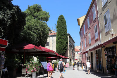 People walking on street amidst buildings in city