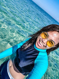 Portrait of happy young woman wearing sunglasses in sea