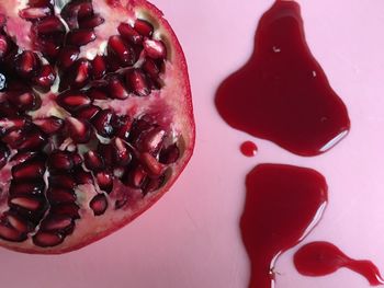 Directly above shot of halved pomegranate on pink table