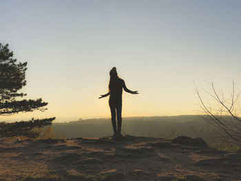 Silhouette person standing on field against sky during sunset