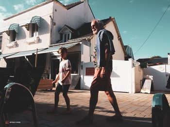 Women standing by buildings in city against sky