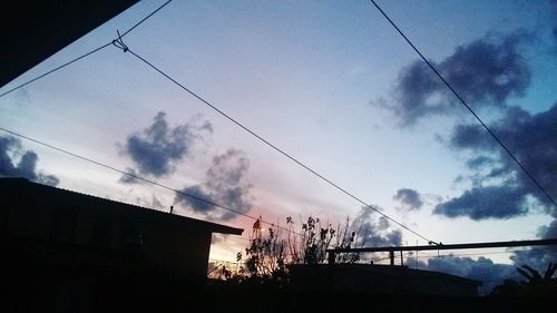 Low angle view of silhouette electricity pylon against sky