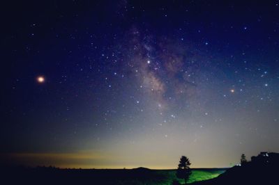 Silhouette landscape against star field at night