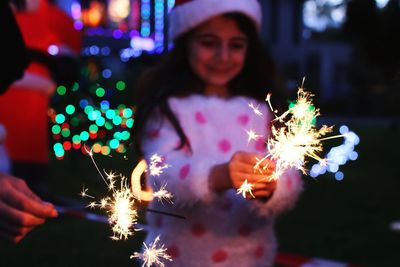 Girl playing with illuminated sparkler at night