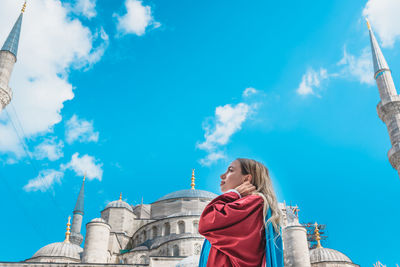 Low angle view of woman looking at buildings against sky