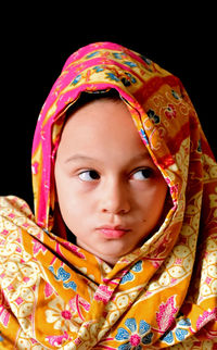 Portrait of cute girl against black background