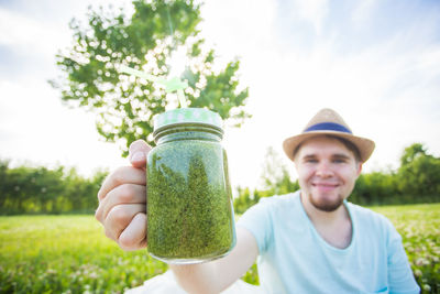 Portrait of smiling man holding plants in jar