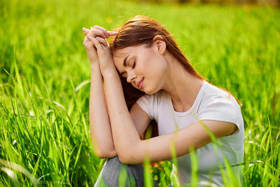 Side view of young woman sitting on field