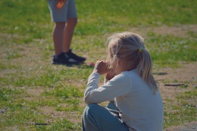 Side view of girl sitting on grassy field