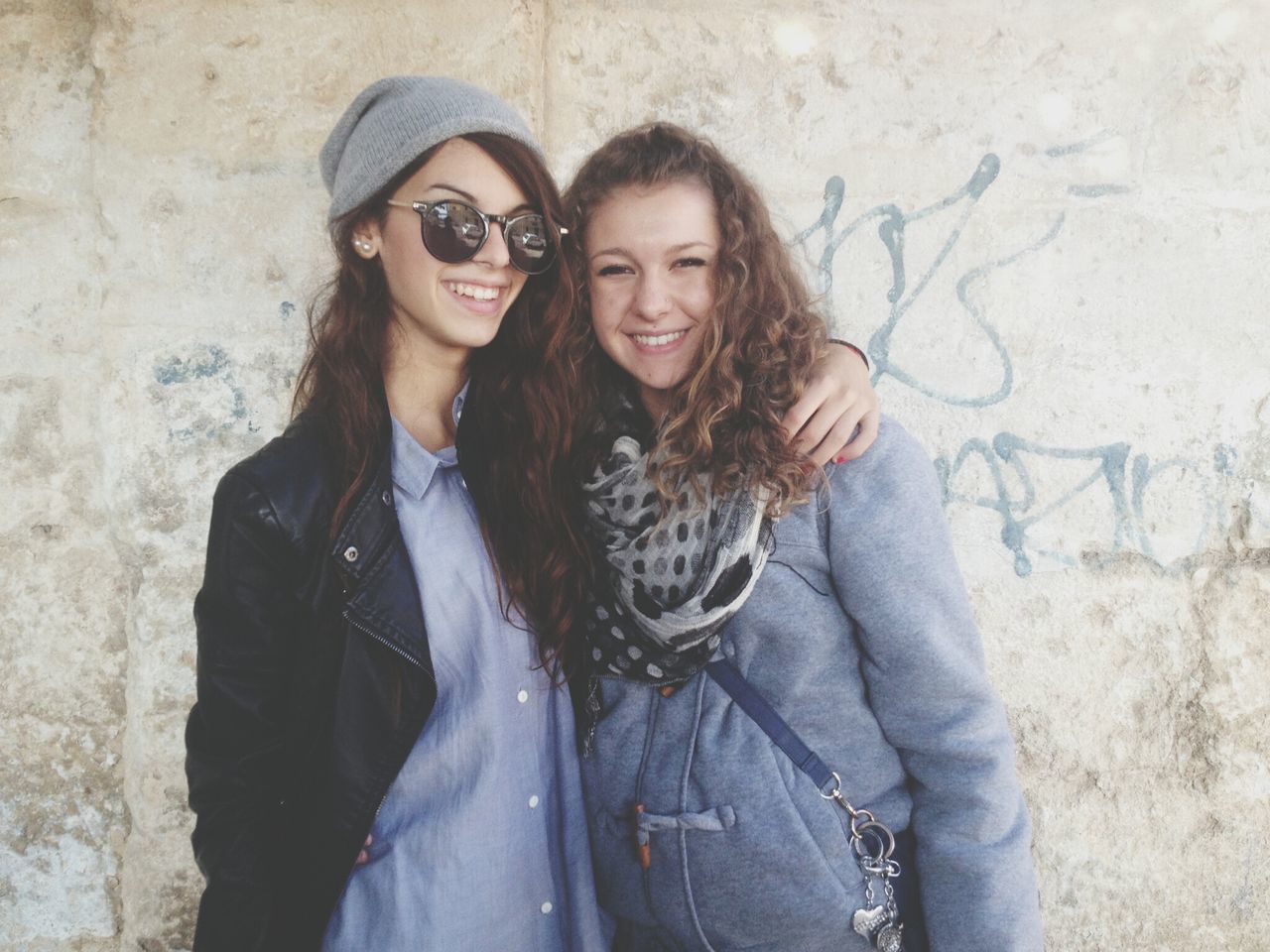 person, portrait, looking at camera, young adult, lifestyles, young women, leisure activity, casual clothing, smiling, front view, standing, three quarter length, happiness, waist up, long hair, wall - building feature, sitting