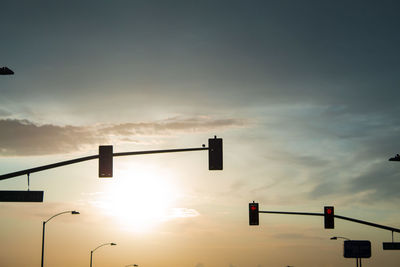 Low angle view of road signals against sky during sunset