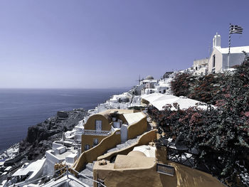 Buildings by sea against clear sky