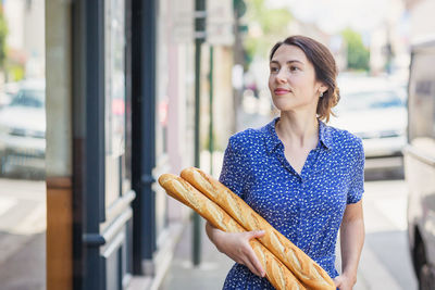 Young woman buying a french baguette