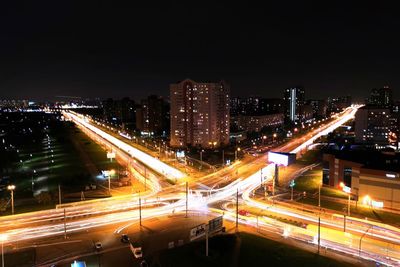 High angle view of light trails on street amidst buildings at night