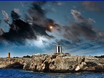 Lighthouse by sea against sky