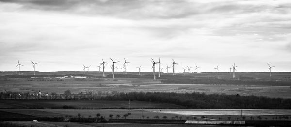 Wind turbines on field against sky