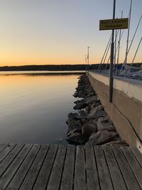 Pier on lake against sky during sunset