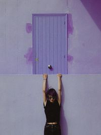 Portrait of young woman standing against wall