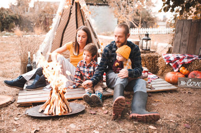 Family resting having picnic outdoors over autumn decor. 