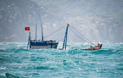 Boat drowning in sea against mountains