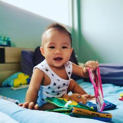 Portrait of cute baby boy sitting on bed at home