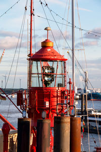 Beacon at harbor by sea against sky