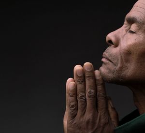 Black man praying to god on gray background with people stock image stock photo