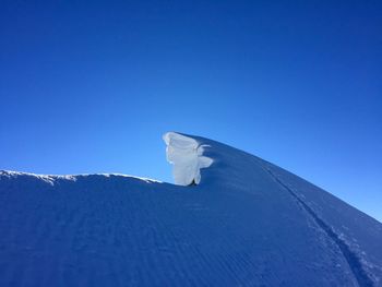 Low angle view of snow covered landscape against clear blue sky