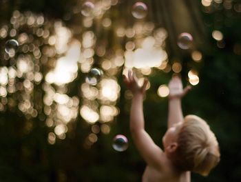 Defocused image of boy playing with bubbles during sunset