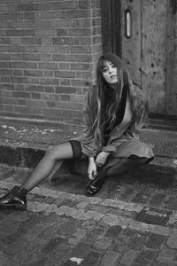 Portrait of woman sitting against wall