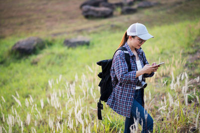 Young woman using mobile phone while standing on field