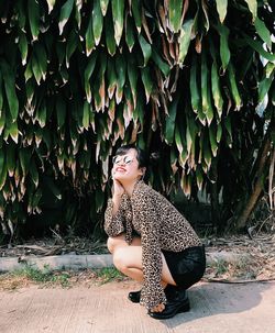 Side view of woman in tiger print blouse and sunglasses sitting outdoors