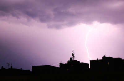Panoramic view of lightning over silhouette buildings