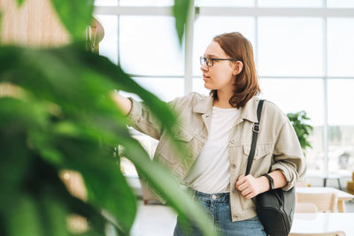 Young brunette teenager girl college student in glasses at modern library, public place