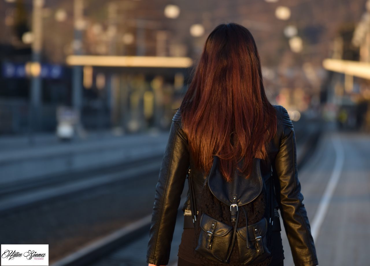 focus on foreground, lifestyles, rear view, long hair, leisure activity, waist up, casual clothing, standing, person, street, side view, three quarter length, headshot, brown hair, young women, young adult, incidental people, warm clothing