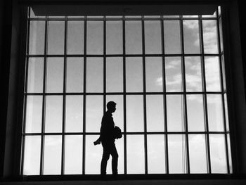 Silhouette man walking by glass window