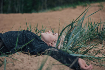 Young woman relaxing on sand at beach against sky