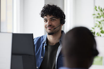 Young man using headset while sitting in office