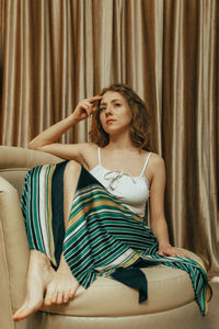 Portrait of young woman sitting on sofa at home