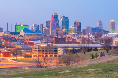 Illuminated buildings in city against clear sky