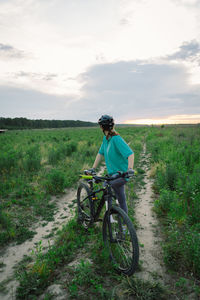 Rear view of man riding bicycle on field