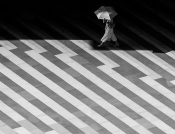 A young woman under umbrella walking on streets