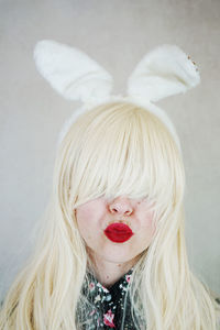 Close-up of woman wearing rabbit ears headband against wall